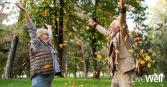 elderly man and woman laughing outside amongst fall leaves